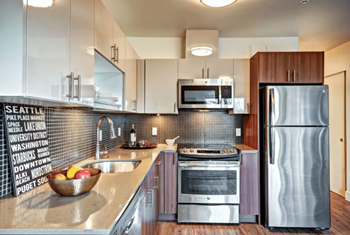 A modern kitchen with a refrigerator on the right and a sink on the left.